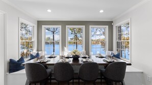 A dining area with a view of a lake, a table set for four, and a bench with blue cushions. - Hillstone Ridge (Mooresville)