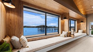 A modern room with large windows, wooden paneling, and a built-in bench with cushions. - Keenan Beach W/beach, Heated Pool & Game Room (Mooresville)