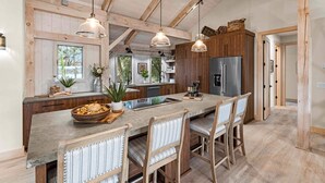 A modern kitchen with a large island, wooden cabinets, and pendant lighting. - Keenan Beach W/beach, Heated Pool & Game Room (Mooresville)