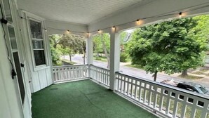 Eine überdachte Veranda mit Kunstgrasantritt und weißen Geländern.