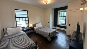 Ein Zimmer mit zwei Betten, einem Fernseher und einem Fenster.