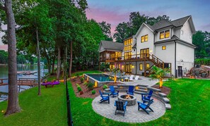 A two-story house with a large deck, a swimming pool, and a fire pit area. - Northshore Landing (Denver)