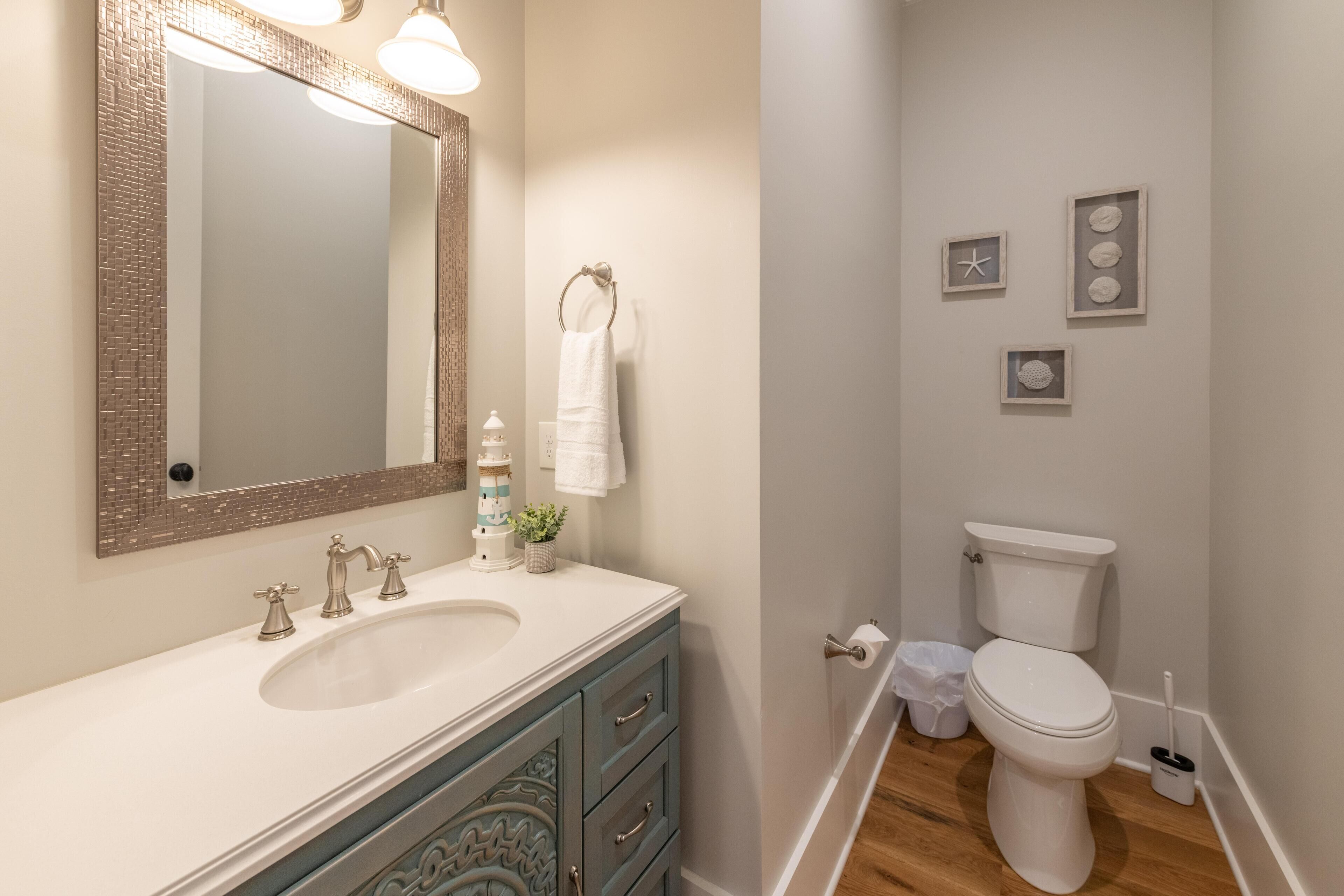 Une salle de bain équipée d’un lavabo, d’un miroir, d’un porte-serviettes, de toilettes et de tableaux encadrés au mur.