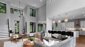 A spacious living area with a grey sofa, wooden coffee table, and a dining area with a kitchen in the background. - Shoreline on Stonemarker (Mooresville)