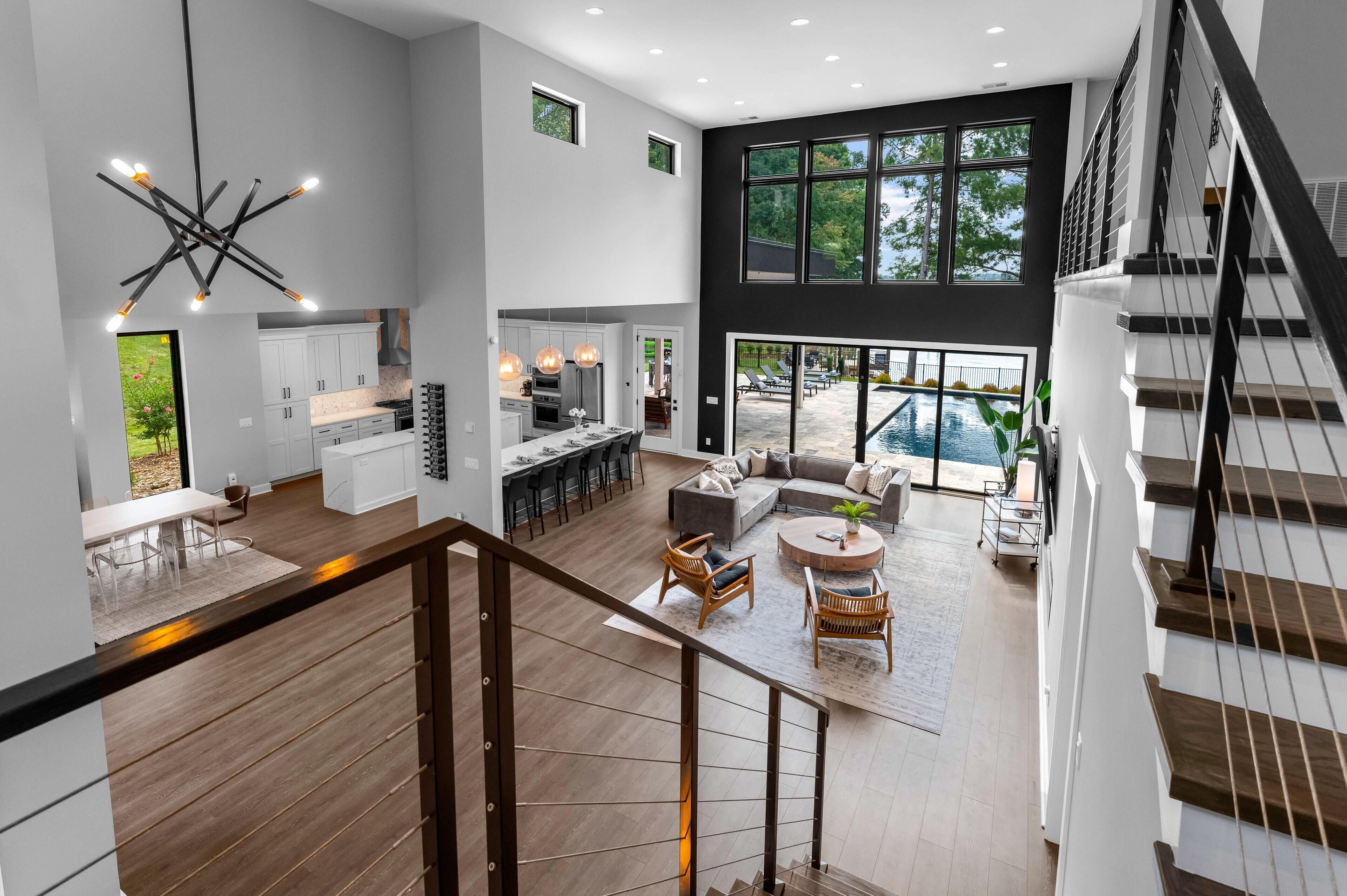 A modern open-plan living area with a kitchen, dining space, and a staircase leading to an upper level.
