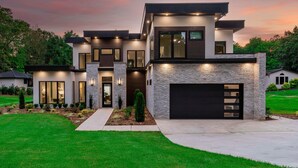 A modern two-story house with a stone facade, large windows, and a garage. - Shoreline on Stonemarker (Mooresville)