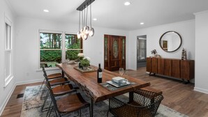 Uma sala de jantar moderna com uma mesa de madeira, cadeiras e um lustre.
