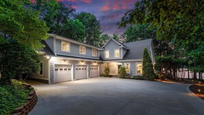 Ein zweistöckiges Haus mit Garage, umgeben von Bäumen und einem gepflegten Rasen.