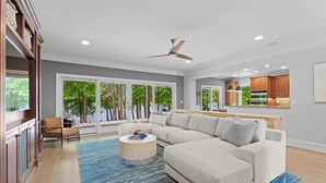 Ein geräumiges Wohnzimmer mit einer großen Eckcouch, einem runden Couchtisch und einem Deckenventilator.