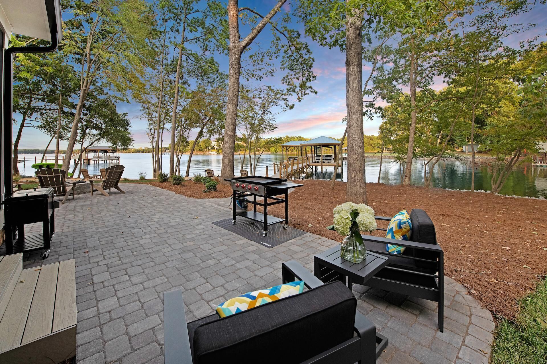 Eine Terrasse im Freien mit Grill, Sitzgelegenheiten und Blick auf einen See.