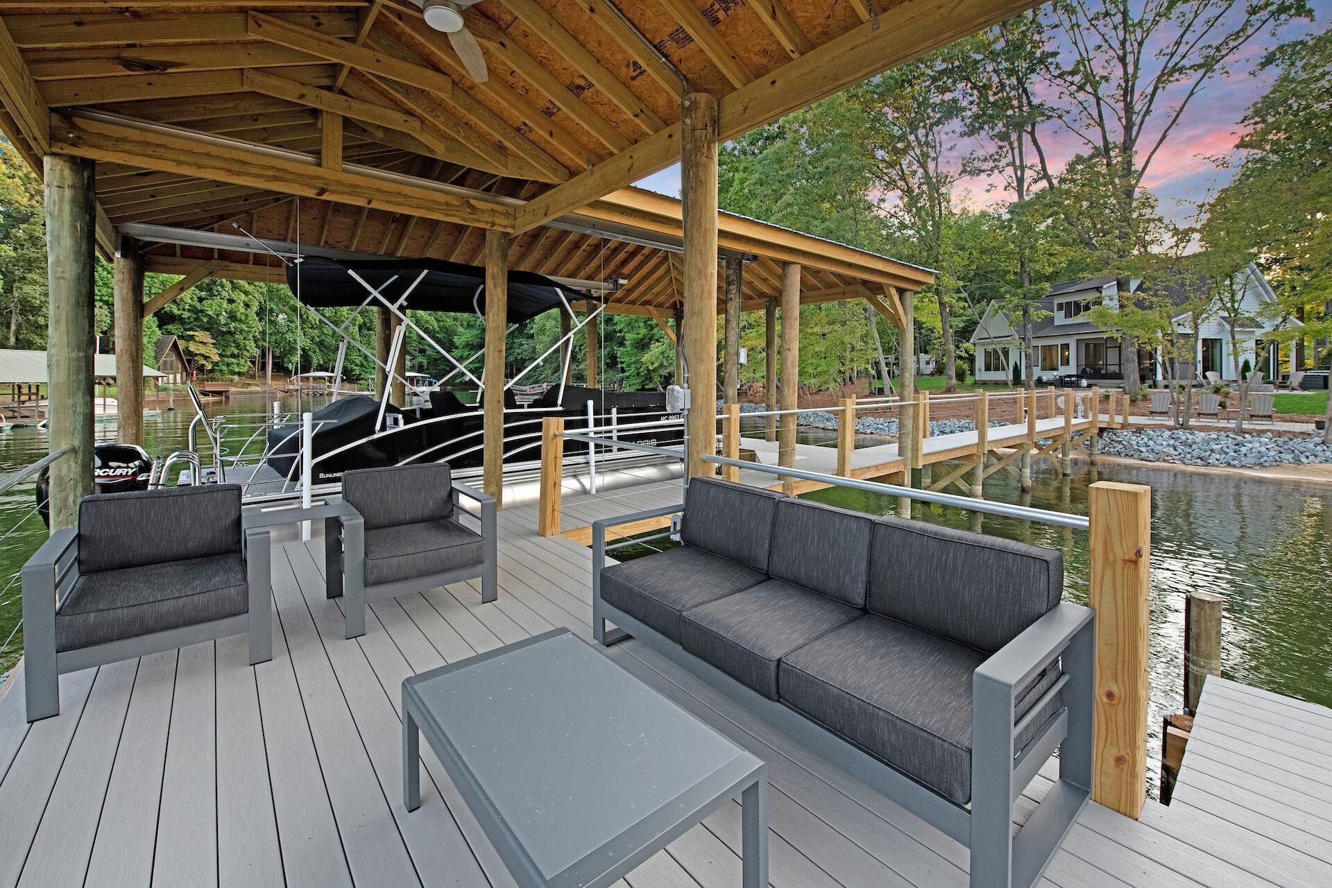 A covered outdoor deck with seating and a view of a dock and boats.