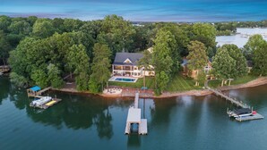An aerial view of a lakeside property with a large house, dock, and boats. - Mallard Vestige (Denver)