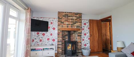 A living room with a fireplace, a television mounted on the wall, a sofa, and a wooden door.
