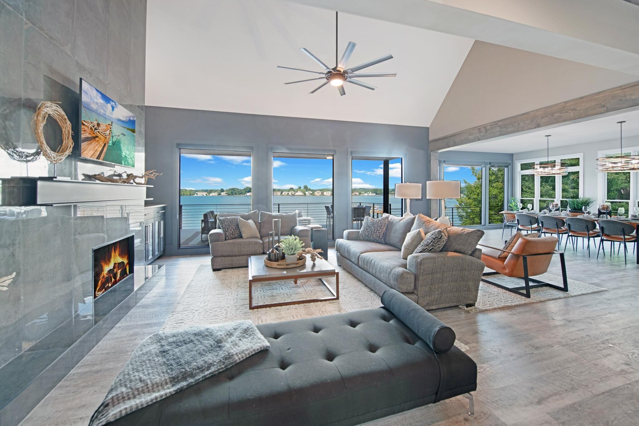 A spacious living room with a fireplace, large windows, and a view of the water.