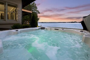 Un bain à remous avec vue sur une étendue d’eau et un coucher de soleil.