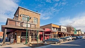 A street view of a commercial area with a variety of storefronts, including a restaurant with outdoor seating and a parking lot with cars. - West Glacier Hot Tub! On Golf Course! Private Home (Flathead County)