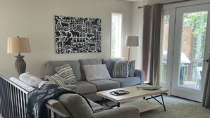 A living room with a grey sofa, two lamps, a coffee table, and a black and white artwork on the wall. - West Glacier Hot Tub! On Golf Course! Private Home (Flathead County)