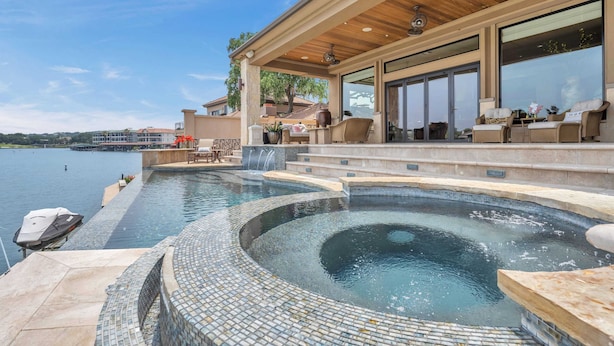Une piscine dotée d’une terrasse en bois et d’un espace salon extérieur.