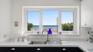 Una cucina con vista sulla spiaggia, un lavello e mobili bianchi.