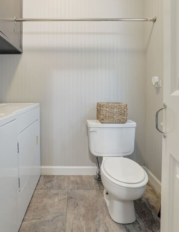 A small, modern bathroom with a toilet, a bidet, and a white cabinet.