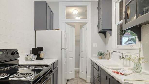 A compact kitchen with a stove, refrigerator, and sink. - Main Street Charmer 3 Bedrooms (New Iberia)