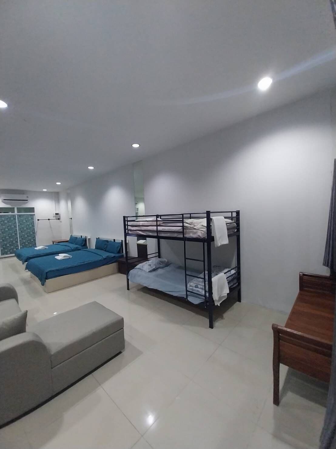 Una habitación de hotel moderna con literas, un sofá, una mesa de madera y un baño con ducha e inodoro.