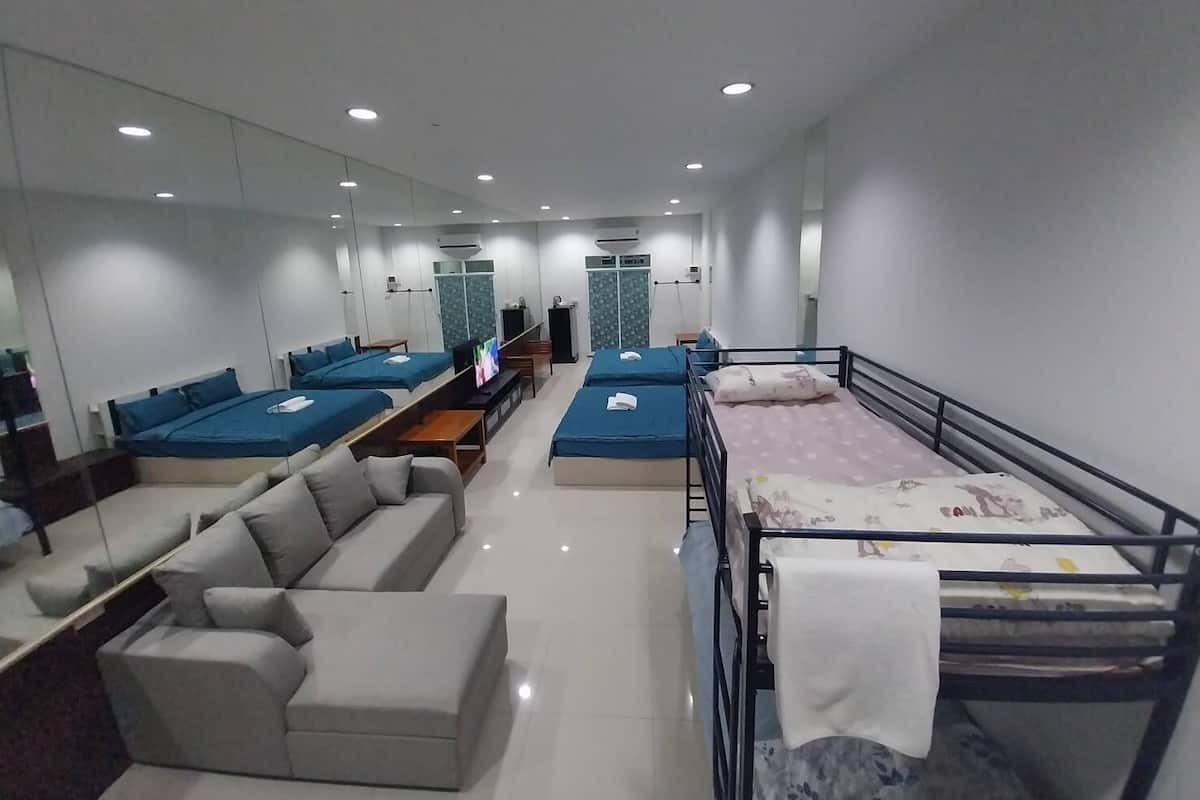 A modern hotel room with a sofa, two single beds, a small table, and a TV.