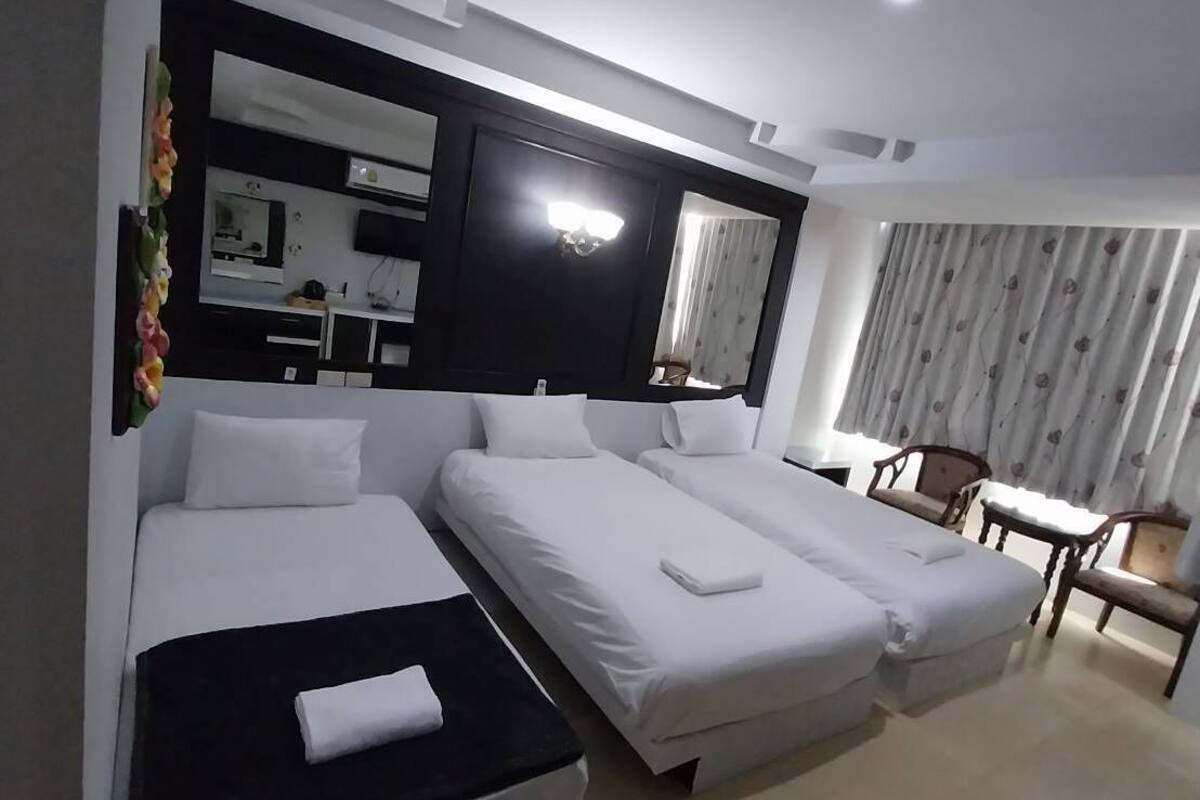 A hotel room with two single beds, a desk, and a chair.