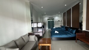 Un salon moderne avec un canapé gris, un canapé bleu et une table basse en bois. Une grande fenêtre offre une vue sur l’extérieur.