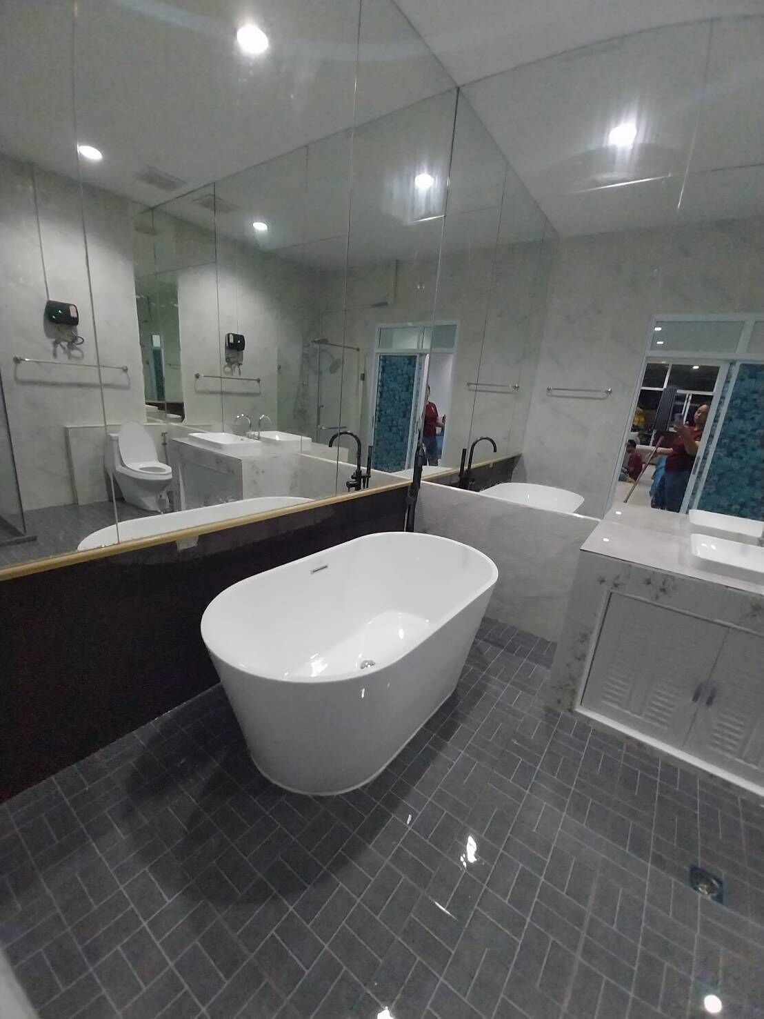 A modern bathroom with a freestanding bathtub, a large mirror, and a vanity with a sink.