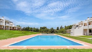 Un área de piscina moderna con una piscina rectangular, rodeada por una terraza pavimentada.