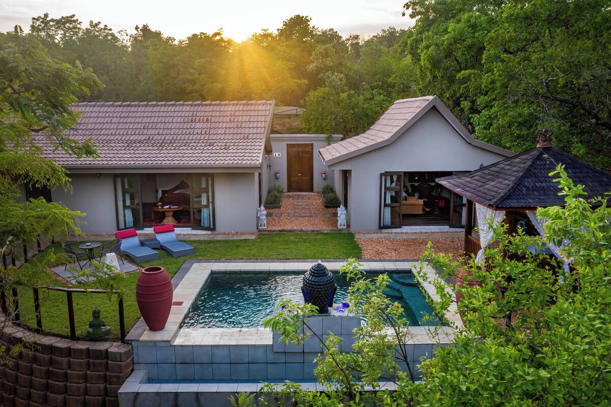 Ein modernes Haus mit Swimmingpool, einer Terrasse mit Sitzgelegenheiten und einem Garten.