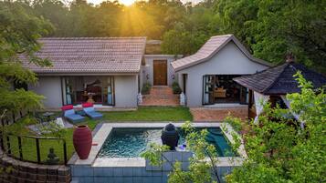 Een modern huis met een zwembad, een terras met zitplaatsen en een tuin.