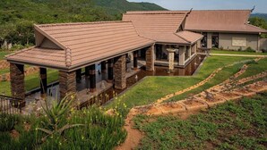 Una casa grande y moderna con un amplio patio, pilares de piedra y un jardín bien cuidado.