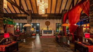 Un vestíbulo amplio con chimenea de piedra, muebles de madera y faroles colgantes.