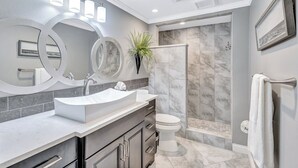 A modern bathroom with a large vanity, a freestanding mirror, and a shower area. - Beach View 1 Bedroom 902 (Sarasota)