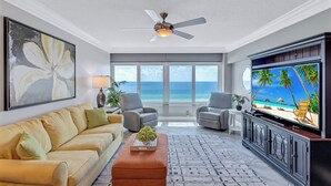 A living room with a sofa, armchairs, a coffee table, a TV, and a ceiling fan. - Beach View 1 Bedroom 902 (Sarasota)