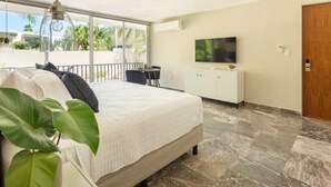 A bedroom with a bed, a TV, a balcony, and a view of palm trees. - Caseiba Peaceful Stays 5 (Merida Yucatan,)