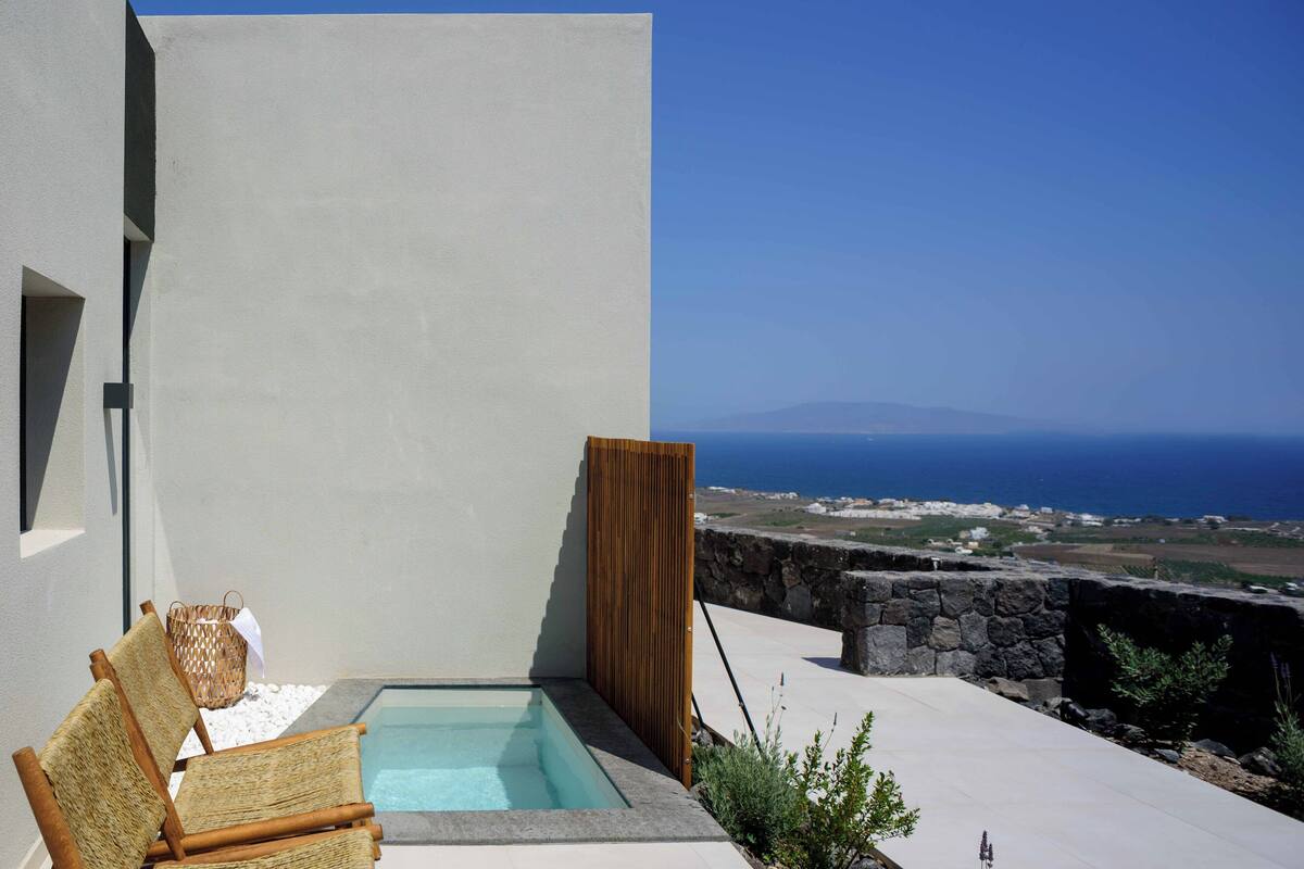 Un área de piscina moderna al aire libre con vista despejada al mar y al paisaje distante.