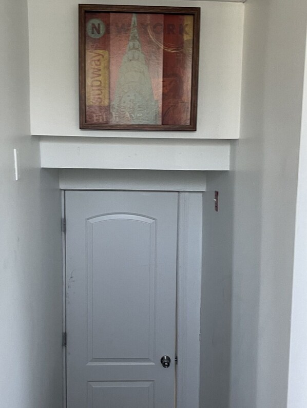 A white door with a simple design, a framed picture above it, and a small sign on the wall to the right.