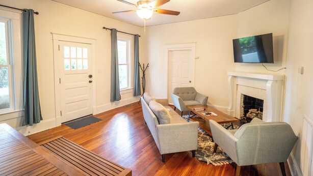 A living room with a sofa, chairs, a fireplace, and a TV mounted on the wall. - Walk to Duke Campus!  3 Bedroom in Trinity Park! (Durham)