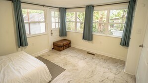 A bedroom with a bed, a suitcase, and a window with curtains. - Walk to Duke Campus!  3 Bedroom in Trinity Park! (Durham)