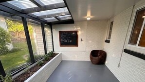 Ein moderner, gut beleuchteter Korridor mit Glasdecke, weißen Backsteinwänden und einer Tafel mit Schrift.
