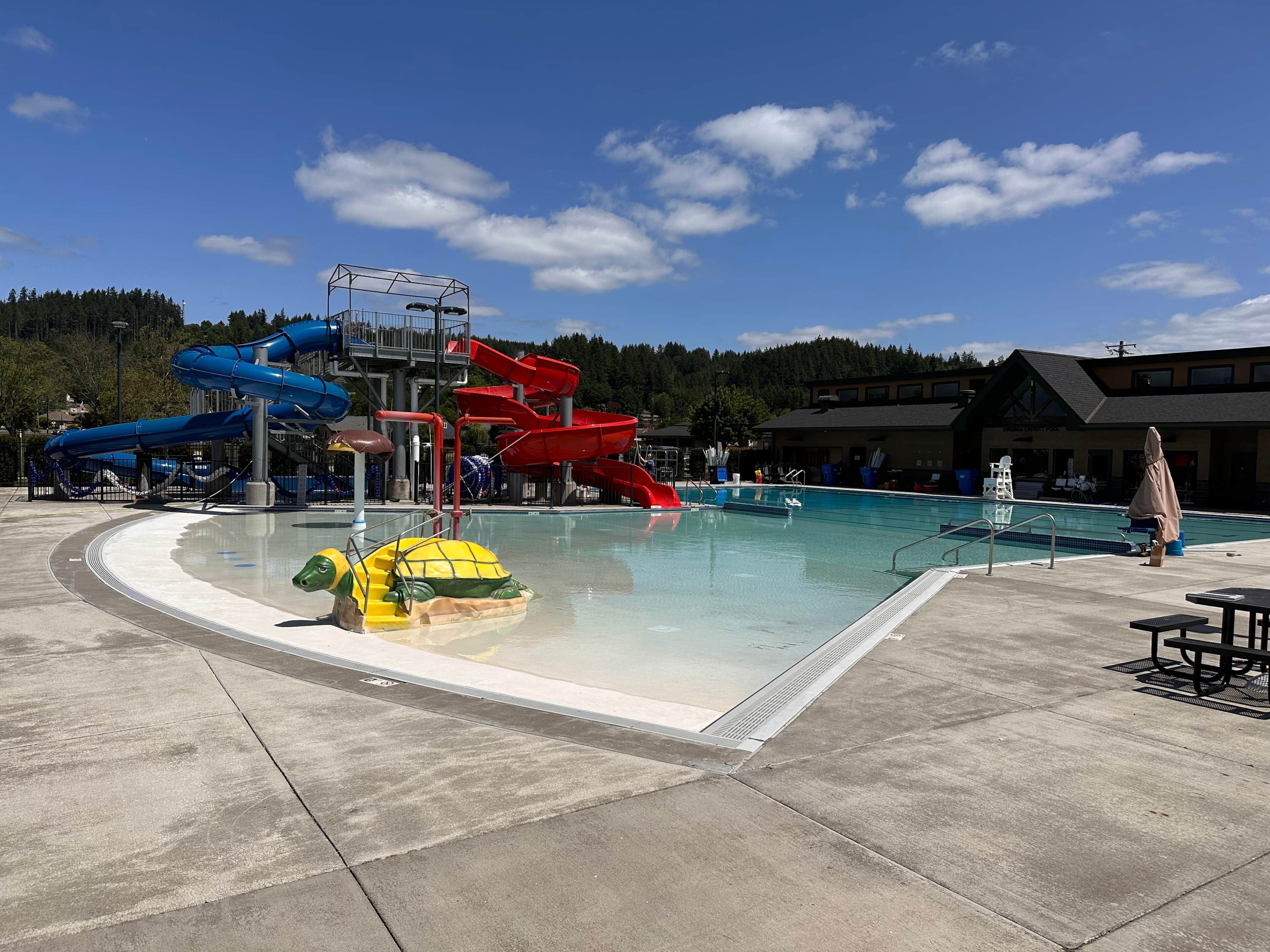 A water park with a pool, slides, and a lifeguard stand.