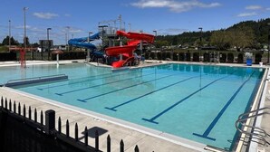 Ein Schwimmbecken mit mehreren Bahnen und Wasserrutschen.