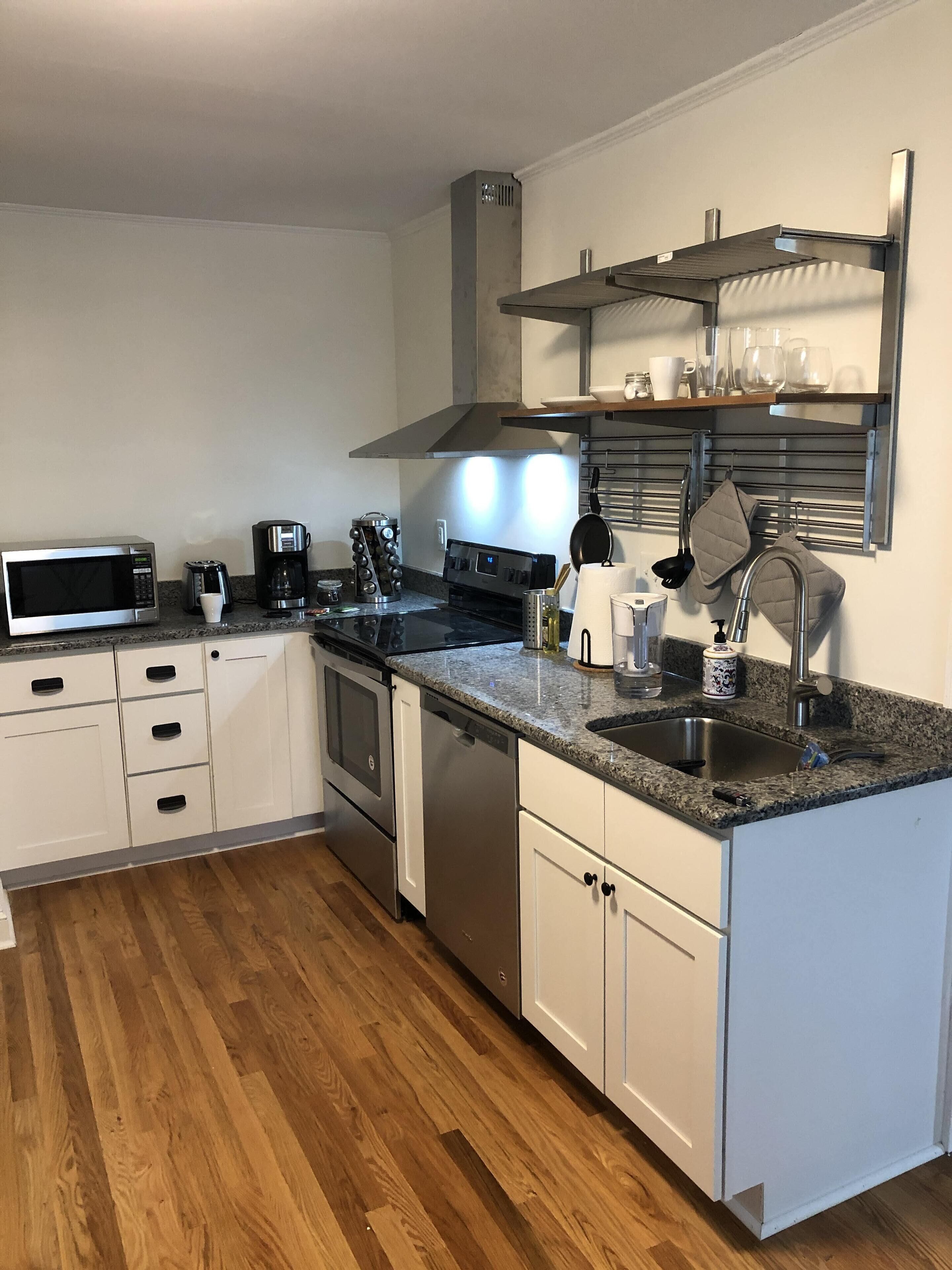 A modern kitchen with white cabinets, stainless steel appliances, and a granite countertop.