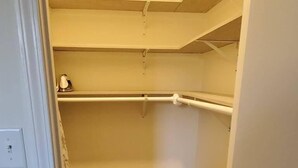 Een smalle gang met houten vloer en een witte deur links.