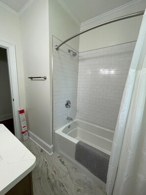 A bathroom with a shower, a bathtub, and a white marble floor.