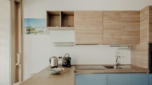 Eine moderne Küche mit hellen Holzschränken, einer blauen Arbeitsplatte und einem Edelstahlspülbecken.