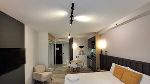 Une chambre d’hôtel équipée d’un lit, d’une télévision, d’un canapé, d’une table à manger et d’un coin cuisine.